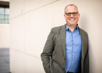 Financial advisor Joe Saul-Sehy, pictured leaning against a wall and smiling.