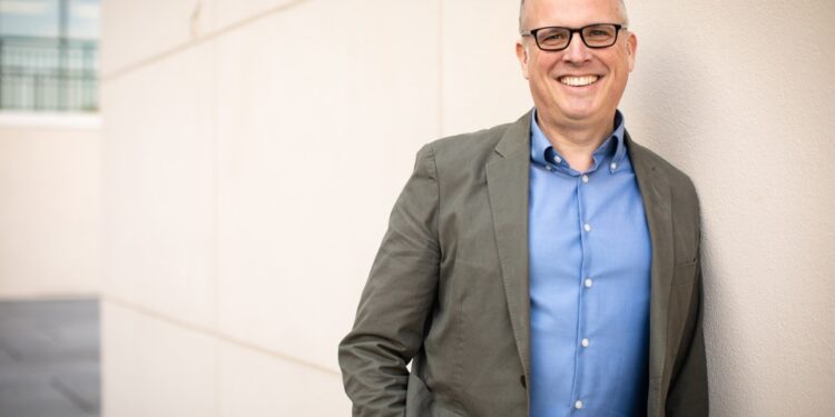 Financial advisor Joe Saul-Sehy, pictured leaning against a wall and smiling.