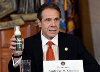 Andrew Cuomo holding a bottle of NYS Clean fluid.