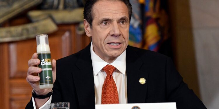 Andrew Cuomo holding a bottle of NYS Clean fluid.