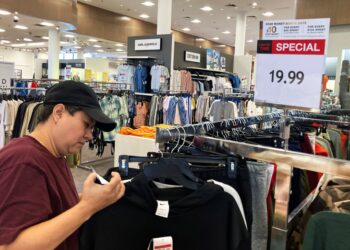 Customer checks price tags at clothing store.