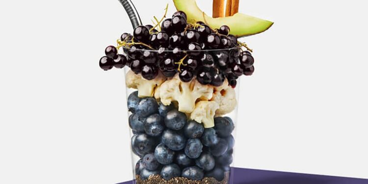 A cup with fruit and other ingredients for a smoothie.