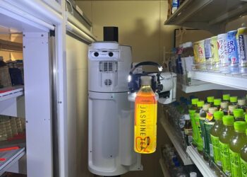 A restocking robot working in a grocery store aisle.