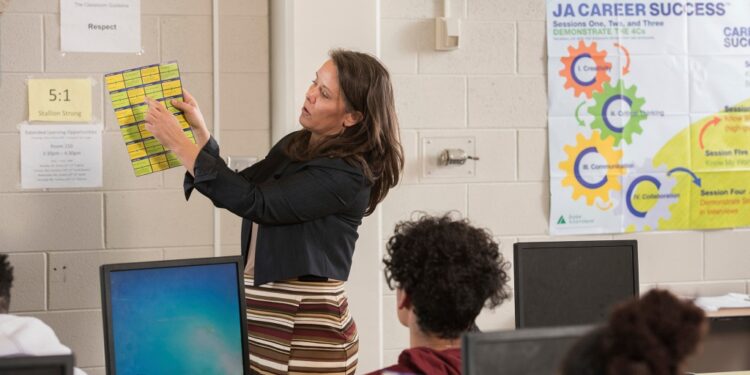 In this photo provided by Junior Achievement USA, volunteer Cammy Elquist LoRé teaches a Colorado Springs, Colo., high school class program.