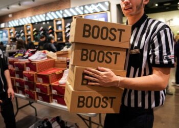 A store employee holding shoe boxes.