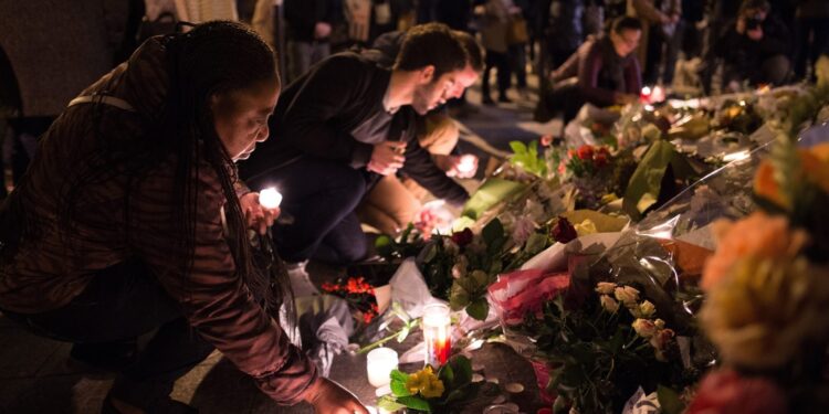 A woman sets down a candle in Rue Alibert, after terror attacks in Paris on Nov. 14, 2015.