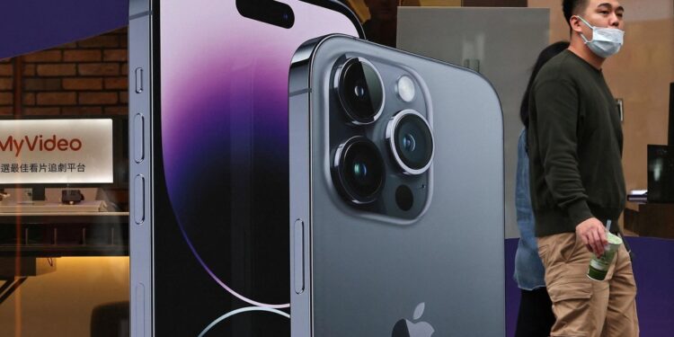 People walk past a poster of iPhones in Taipei, Taiwan.