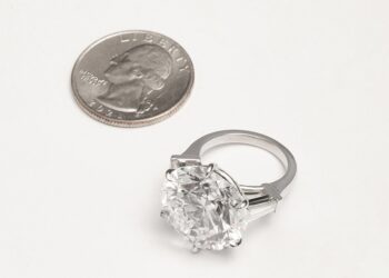 The diamond ring next to a quarter.