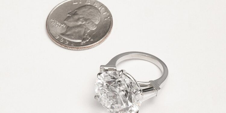 The diamond ring next to a quarter.