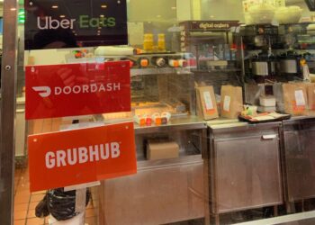 A restaurant with three signs for UberEats, Doordash and Grubhub.