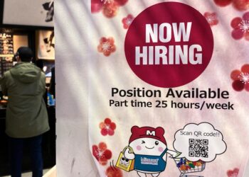 A hiring sign is displayed at a grocery store