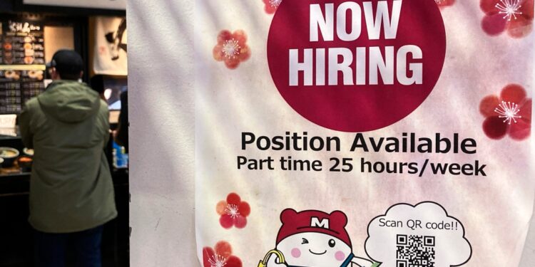 A hiring sign is displayed at a grocery store