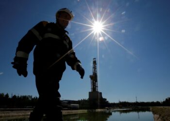 A worker walks past a drilling rig