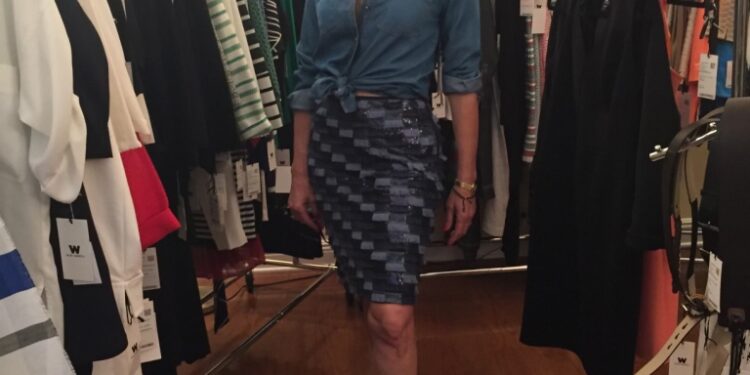 Andrea Greenspan standing between racks of clothing.