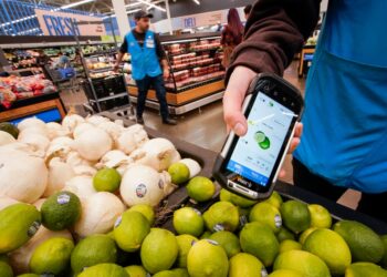A worker scans onions, limes, and other produce inside a Walmart.