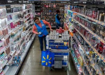 A Walmart employee organizes beauty products.