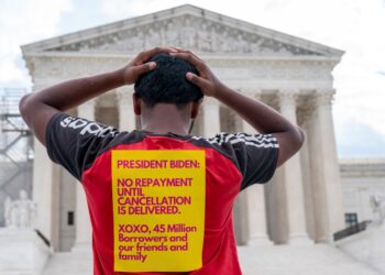Protesters holding signs advocating for the cancellation of student debt stand in front of the United States Supreme Court