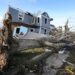 An overturned tree sits in front of a tornado damaged home in Mayfield, Ky., on Dec. 11, 2021, after a tornado ripped through the area.