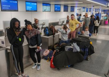 Travelers await at the departure counter at the United Airlines terminal at Los Angeles International Airport.