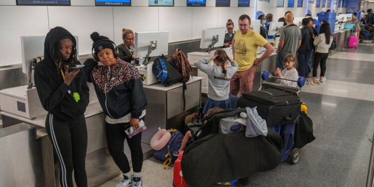 Travelers await at the departure counter at the United Airlines terminal at Los Angeles International Airport.
