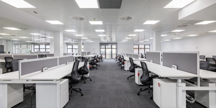 Modern corporate open office in minimalist modern design in whites and greys, empty office workstations.