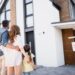 Back view of a family standing near a 'Sold' sign in front of a house