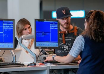A airline agents helps a travelers in the departures area of Terminal B at LaGuardia Airport, Tuesday, June 27, 2023
