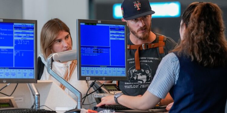A airline agents helps a travelers in the departures area of Terminal B at LaGuardia Airport, Tuesday, June 27, 2023