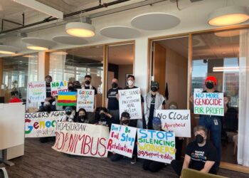 A large group of Google employees hold signs protesting their company's participation in "Project Nimbus."
