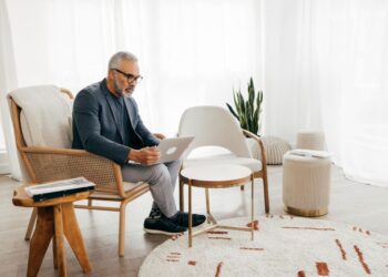 A man sitting in a chair using a laptop