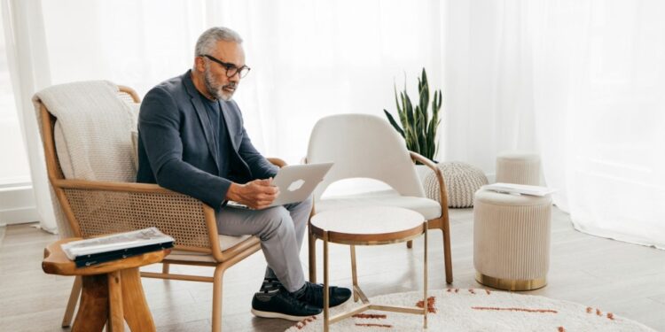 A man sitting in a chair using a laptop