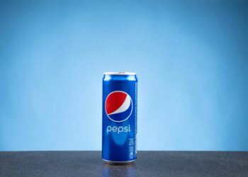 A can of Pepsi on a flat surface against a blue backdrop.