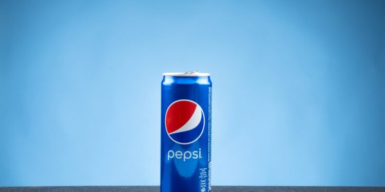 A can of Pepsi on a flat surface against a blue backdrop.