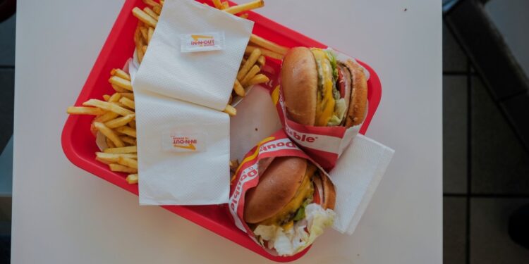 An In-N-Out burger, with a juicy beef patty, melted cheese, fresh lettuce, and tomato all stacked between two soft buns.