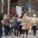 People commuting during rush hour across a busy Manhattan crosswalk in New York City.