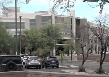 A Wells Fargo office building with parked cars in front, where an employee was found deceased in her cubicle.