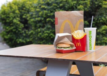 McDonald's burger, fries and soda on outdoor table.