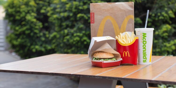 McDonald's burger, fries and soda on outdoor table.