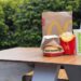 McDonald's burger, fries and soda on outdoor table.