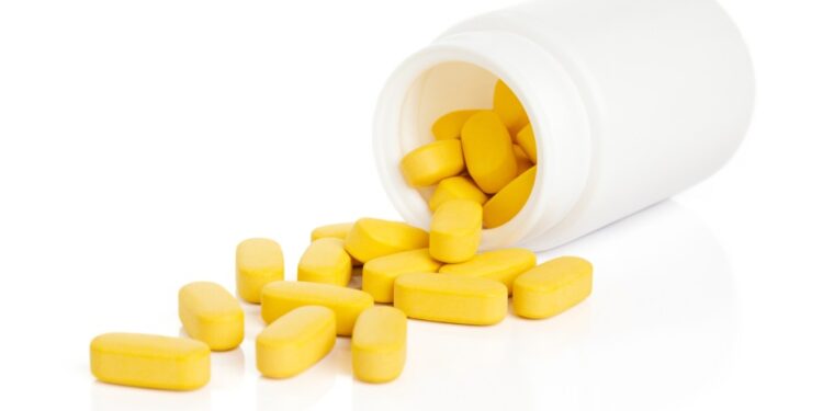 Yellow pills spilling out of a white bottle