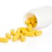Yellow pills spilling out of a white bottle