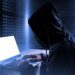 A person in a black hoodie using a laptop, symbolizing a data breach exposing personal information of individuals