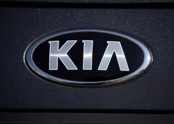 The company logo shines off the hood of a 2021 K5 sedan on display in the Kia exhibit at the Denver auto show Friday, Sept. 17, 2021