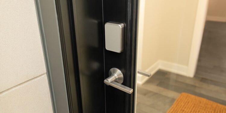 A silver door lock on a black door above a silver handle