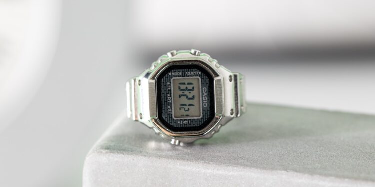 Vertical shot of the Casio Ring Watch sitting on the edge of a gray clock. In the background, you can see other blurry clocks.