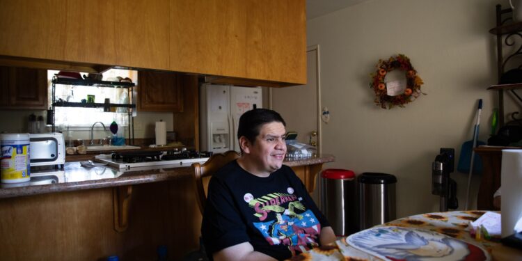 A man sits at a kitchen table.
