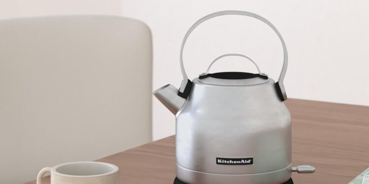 Electric kettle on table between a cup and a book