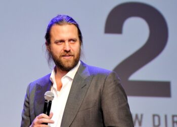 Director Carl Erik Rinsch in a suit holding a microphone at the New Directors' Showcase in Los Angeles, September 23, 2015