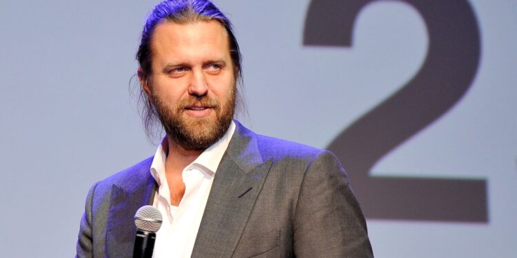Director Carl Erik Rinsch in a suit holding a microphone at the New Directors' Showcase in Los Angeles, September 23, 2015