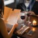 Cheerful couple at a restaurant table, reading a menu, with wine glasses and a candle on the table